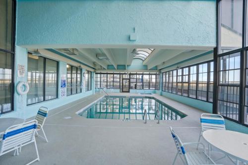 una piscina en un edificio con mesas y sillas en Windemere 702 - Oceanfront - Ocean Drive Section, en Myrtle Beach