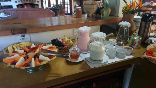 a table with a bowl of fruit and a plate of milk at Pousada da Mata in Cunha