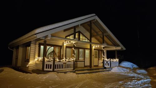 ein Haus mit Weihnachtslichtern im Schnee in der Unterkunft Villa Aurora, Himos in Jämsä