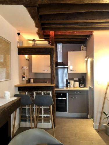 une cuisine avec un comptoir et des tabourets dans une pièce dans l'établissement Appartement au cœur de Paris /quartier Montorgueil, à Paris
