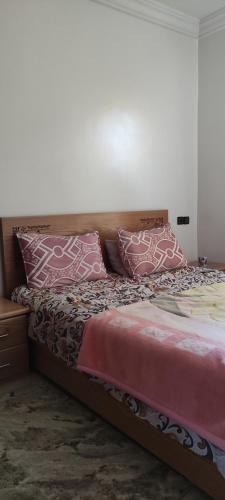 a bed with pink and white pillows on it at رياض النخيل in Aïn el Apuda
