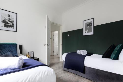 - une chambre avec 2 lits et un mur vert dans l'établissement Stylish & Spacious 3bed in Putney, à Londres