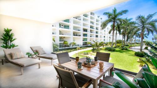 an apartment patio with a table and chairs and palm trees at Aria Ocean View Condo 206 by Kivoya in Nuevo Vallarta 