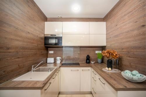 a kitchen with white cabinets and a wooden wall at LaVida Deluxe villa Hajdúszoboszló in Hajdúszoboszló