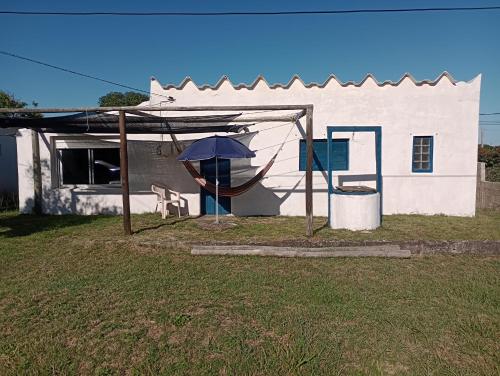 a house with an umbrella and a hammock in front of it at Antoniopolis in Rocha