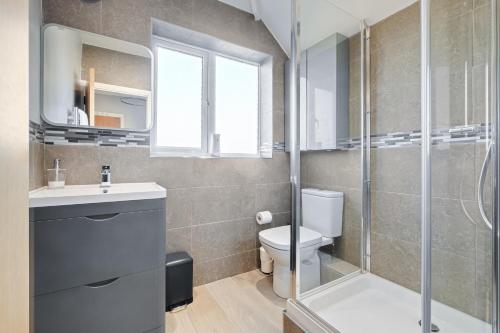 a bathroom with a shower and a toilet and a sink at Stylishly Decorated 3-bed House in Bedford