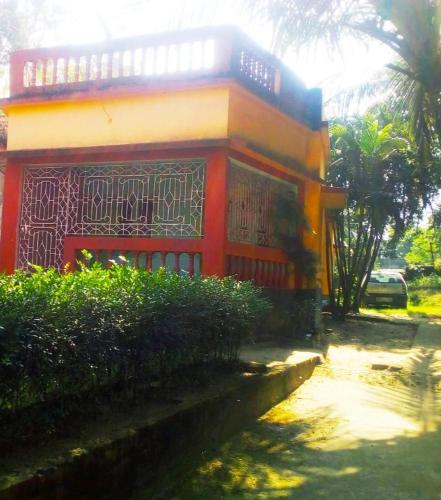 una casa roja y amarilla con una valla delante en Sonarbangla en Digha