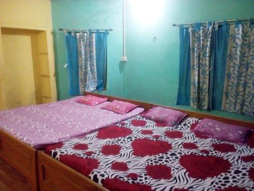 a bedroom with a bed with red and white comforter at Sonarbangla in Digha