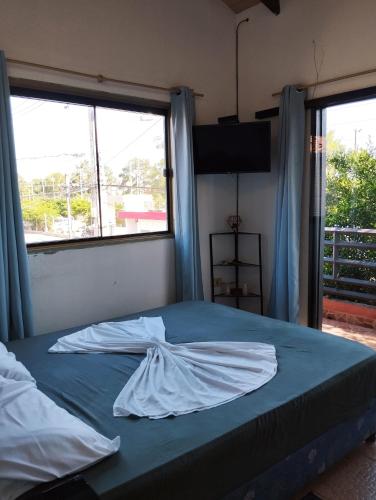 Bett in einem Zimmer mit zwei großen Fenstern in der Unterkunft Mangoty Apartamento in Luque