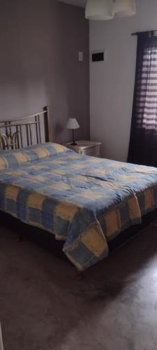 - une chambre dotée d'un lit avec une couverture bleue et jaune dans l'établissement La chacrita en San Miguel del Monte, à San Miguel del Monte