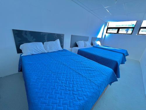 two beds in a room with blue lighting at Hotel Citadin zona 5 in Guatemala