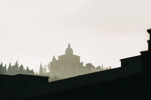 a silhouette of a building on a hill in the fog at A Casa dello Steno - Unicità Rustica in Bologna