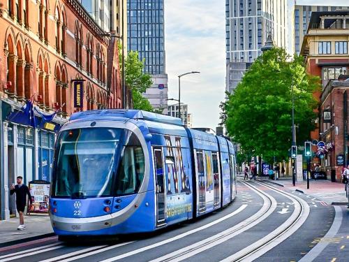 a blue tram on a city street with buildings at Luxury Rooms just off broad St Walking distance to city centre in Birmingham