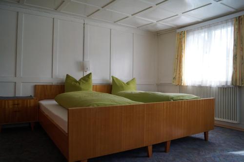 a bedroom with a bed with green pillows and a window at Ferienhaus Lila in Hittisau