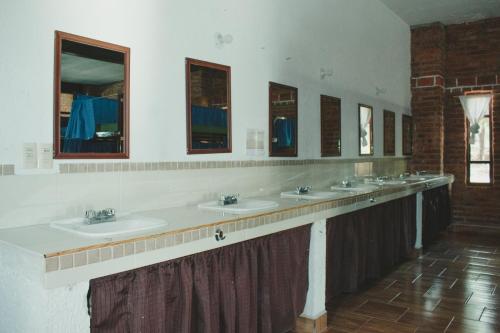 een badkamer met een rij wastafels en spiegels bij La Piedra del Tesoro Campamento in El Zepo