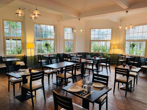 een restaurant met tafels, stoelen en ramen bij Hotel du Parc in Dinard