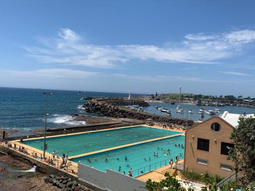 a large swimming pool next to the ocean with people in it at 2 bedroom small unit 1 minute walk to shopping centre NO PARKING SLOT in Wollongong