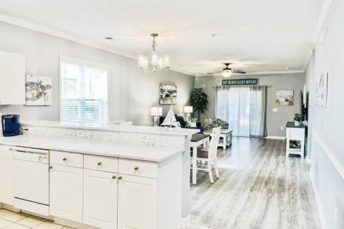 a kitchen with white cabinets and a dining room at Barefoot Beach Haven: Resort Access in North Myrtle Beach