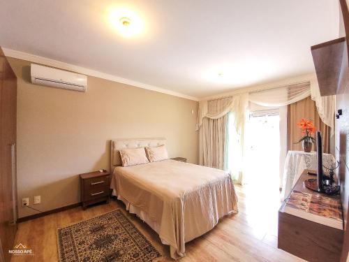 1 dormitorio con cama y ventana grande en NossoApê Guarua: Piscina | Churrasqueira | Ar-condicionado, en Juiz de Fora