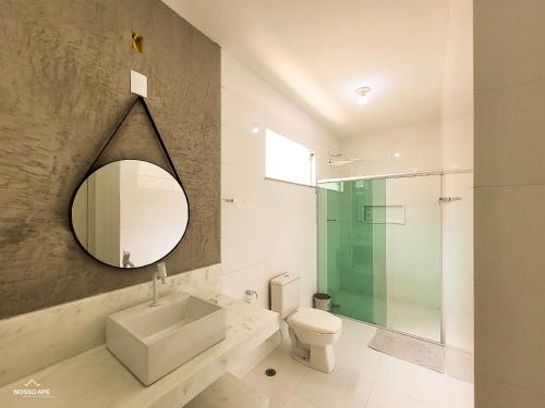uma casa de banho com um lavatório, WC e um espelho. em NossoApê Guarua: Piscina | Churrasqueira | Ar-condicionado em Juiz de Fora