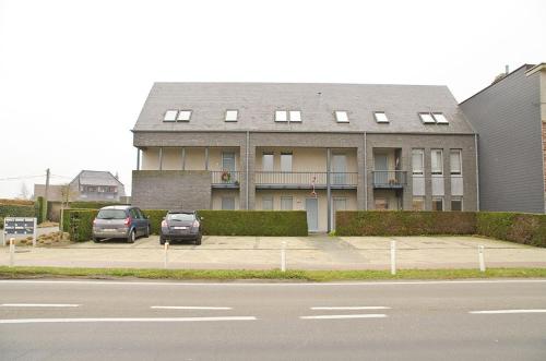 een gebouw met twee auto's geparkeerd op een parkeerplaats bij Hotel Apartments Belgium I in Geel