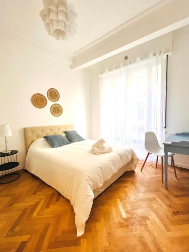 une chambre blanche avec un grand lit et un bureau dans l'établissement Cœur d'Azur Appartement, à Nice