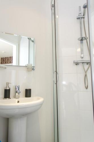 a bathroom with a sink and a shower with a mirror at Trivelles Eccles in Manchester