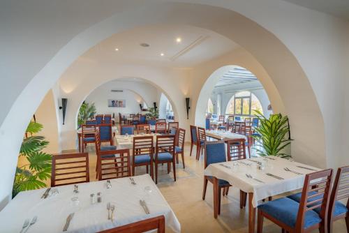 un restaurante con mesas blancas y sillas azules en Mediterranee Hammamet- Families and Couples Only en Hammamet