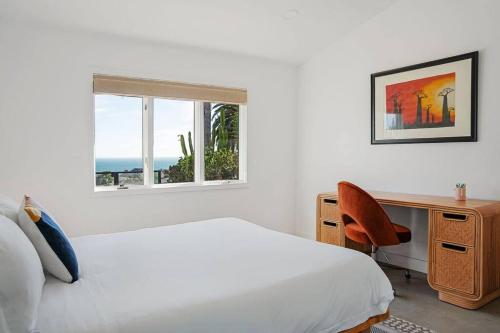 a bedroom with a bed and a desk and a window at The Broad Beach House in Malibu