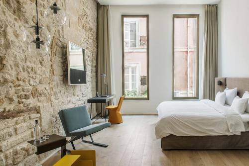 um quarto com uma cama e uma parede de tijolos em Hôtel de Tourrel, Saint Rémy de Provence, a Member of Design Hotels em Saint-Rémy-de-Provence