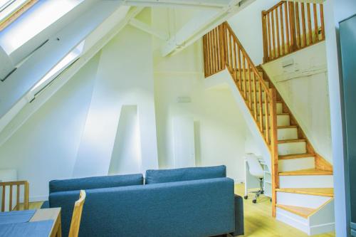 - un salon avec un canapé bleu et un escalier dans l'établissement Quartier historique de Mantes, au pied de la cathédrale avec vue directe sur celle-ci, à Mantes-la-Jolie