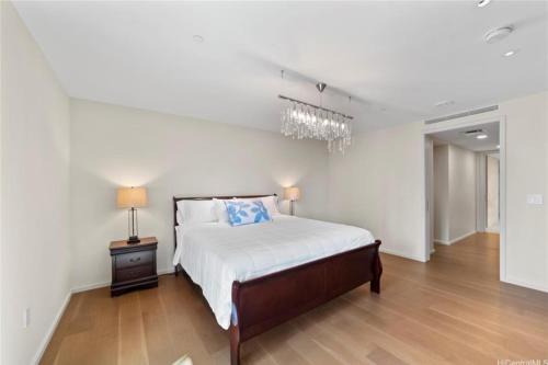 a white bedroom with a bed and a chandelier at Park lane 2/2 in Honolulu