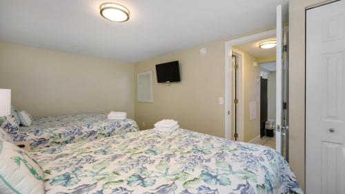 a bedroom with two beds and a tv on the wall at Blue Moon - 3rd Row - Ocean Drive Section in Myrtle Beach