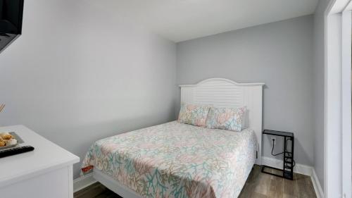 a small bedroom with a bed and a white wall at Blue Moon - 3rd Row - Ocean Drive Section in Myrtle Beach