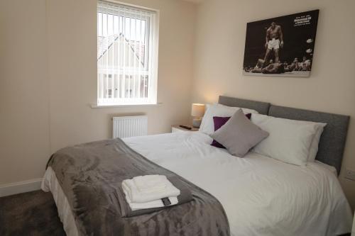 a bedroom with a bed with two towels on it at Spacious New Build - Free Parking & TV in each Bedroom in Macclesfield