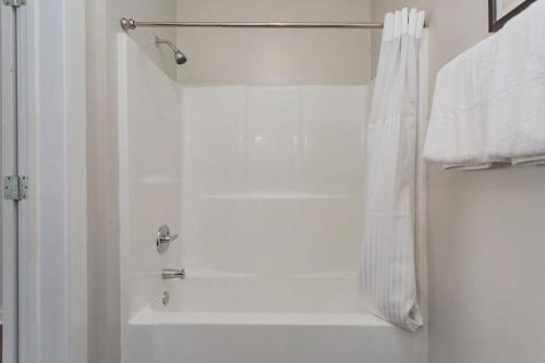 La salle de bains est pourvue d'une douche avec un rideau de douche blanc. dans l'établissement TWO CozySuites Classy Music Row Condos w parking, à Nashville