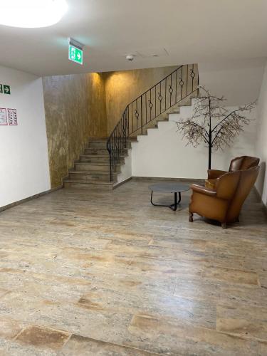 a lobby with a staircase and a chair and a plant at Gastpark Hotel in Manching