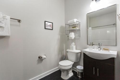 a white bathroom with a toilet and a sink at TWO CozySuites Stylish Music Row Condos w parking in Nashville