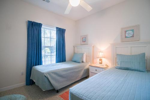 a bedroom with two beds and a window with blue curtains at Barefoot Resort - Arbor Trace 523 - Windy Hill in North Myrtle Beach