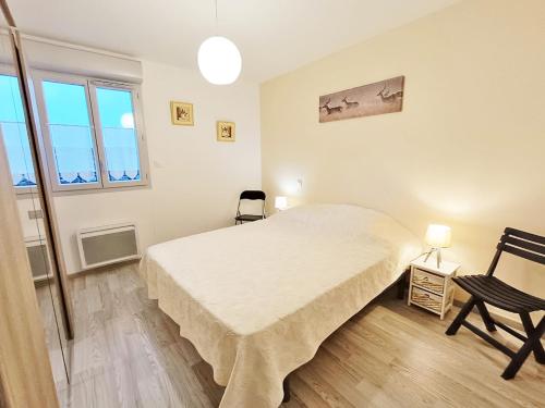 une chambre blanche avec un lit et une chaise dans l'établissement Sylvie8, T2, centre Luchon, jardin, 4 personnes, à Luchon