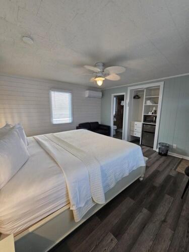 a bedroom with a white bed and a kitchen at Island Guesthouse and Motel OBX in Manteo