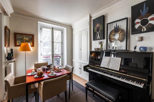 - un salon avec un piano, une table et des chaises dans l'établissement Appartement Cuneta - Welkeys, à Paris