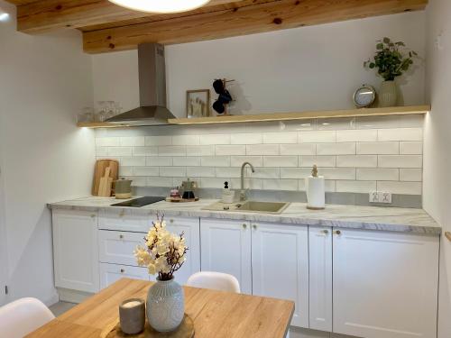 a kitchen with white cabinets and a wooden table at Cozy House in Świnoujście