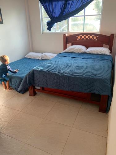 Un niño pequeño parado en una cama en un dormitorio en Sirena azul, 