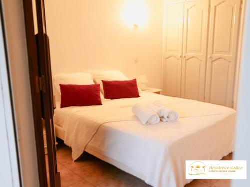 a bedroom with a bed with white sheets and red pillows at Résidence Galice in Les Trois-Îlets