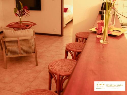 a kitchen with a table and stools and a room at Résidence Galice in Les Trois-Îlets