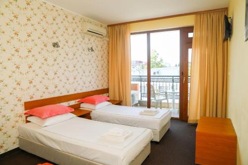 a hotel room with two beds and a balcony at Family hotel Deykin in Sunny Beach