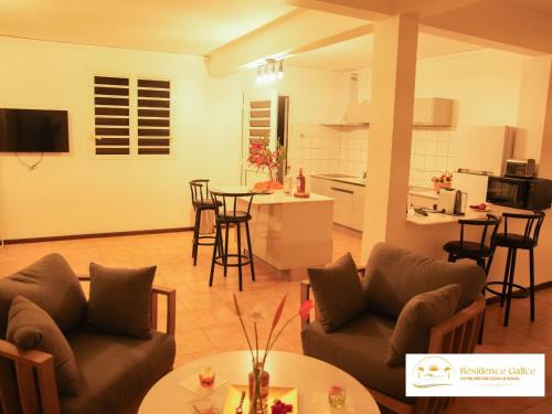 a living room with a couch and a kitchen at Résidence Galice in Les Trois-Îlets