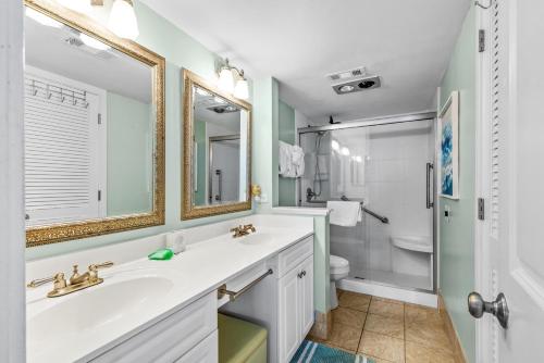 a bathroom with a sink and a toilet and a mirror at Ocean Creek Resort E8 -Oceanfront - Windy Hill in Myrtle Beach