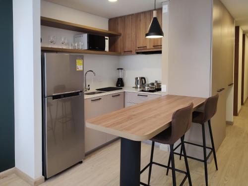 a kitchen with a wooden table and a refrigerator at The Hood 102, Modern and Luxury Apartments in Bogotá
